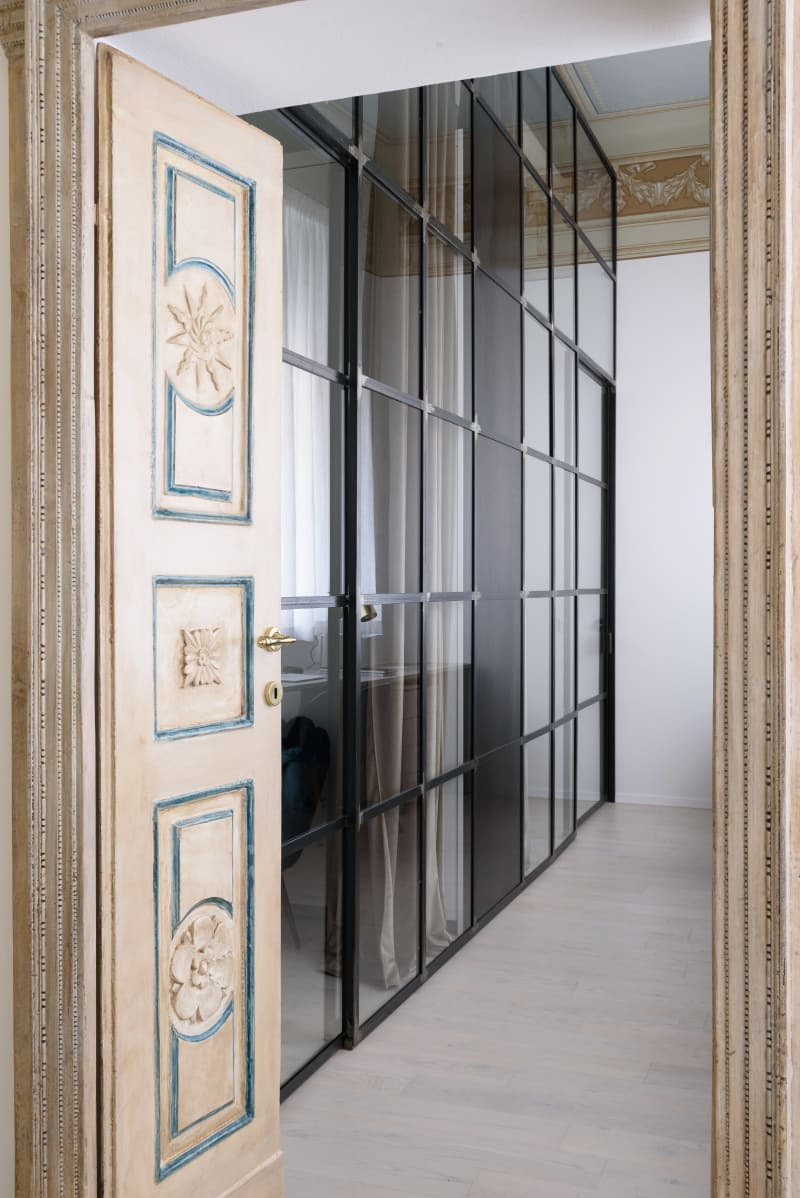 A framed black glass wall runs through the Lelefante apartment, acting as a central divider.