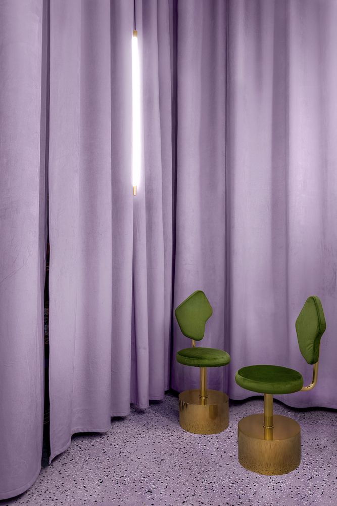 Sculptural olive green chairs pop beautifully against  the lilac curtains draped throughout the shop.