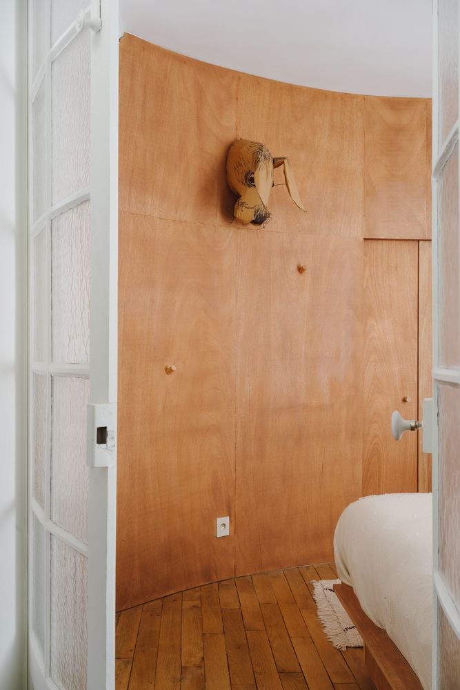 Hanging sculptural art and lots of wood lead into the primary bedroom of the Jean Benoit Vétillard-renovated Gambetta apartment building in Paris.
