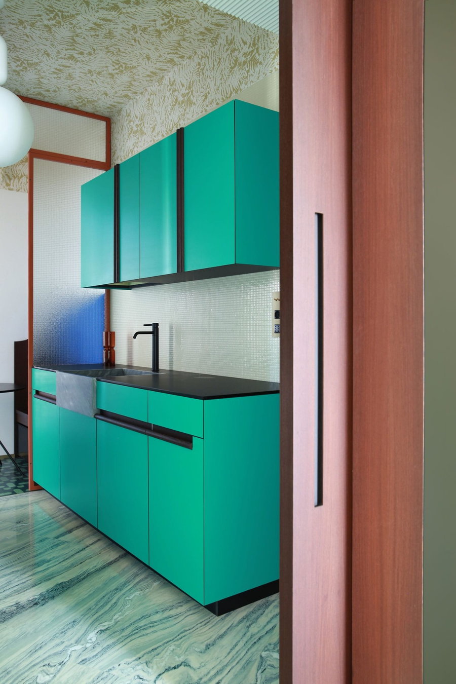 The colorful teal kitchen area inside the renovated Teorema Milanese