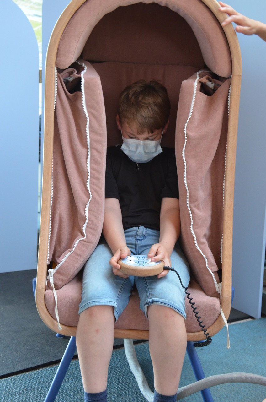 Small boy wearing face mask its inside Audrain Alexia's innovative OTO Chair.