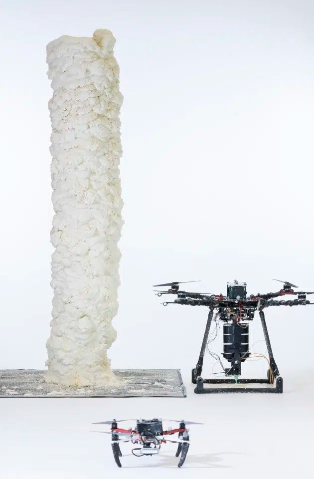 3D printing drones assemble a tall foam tower. 