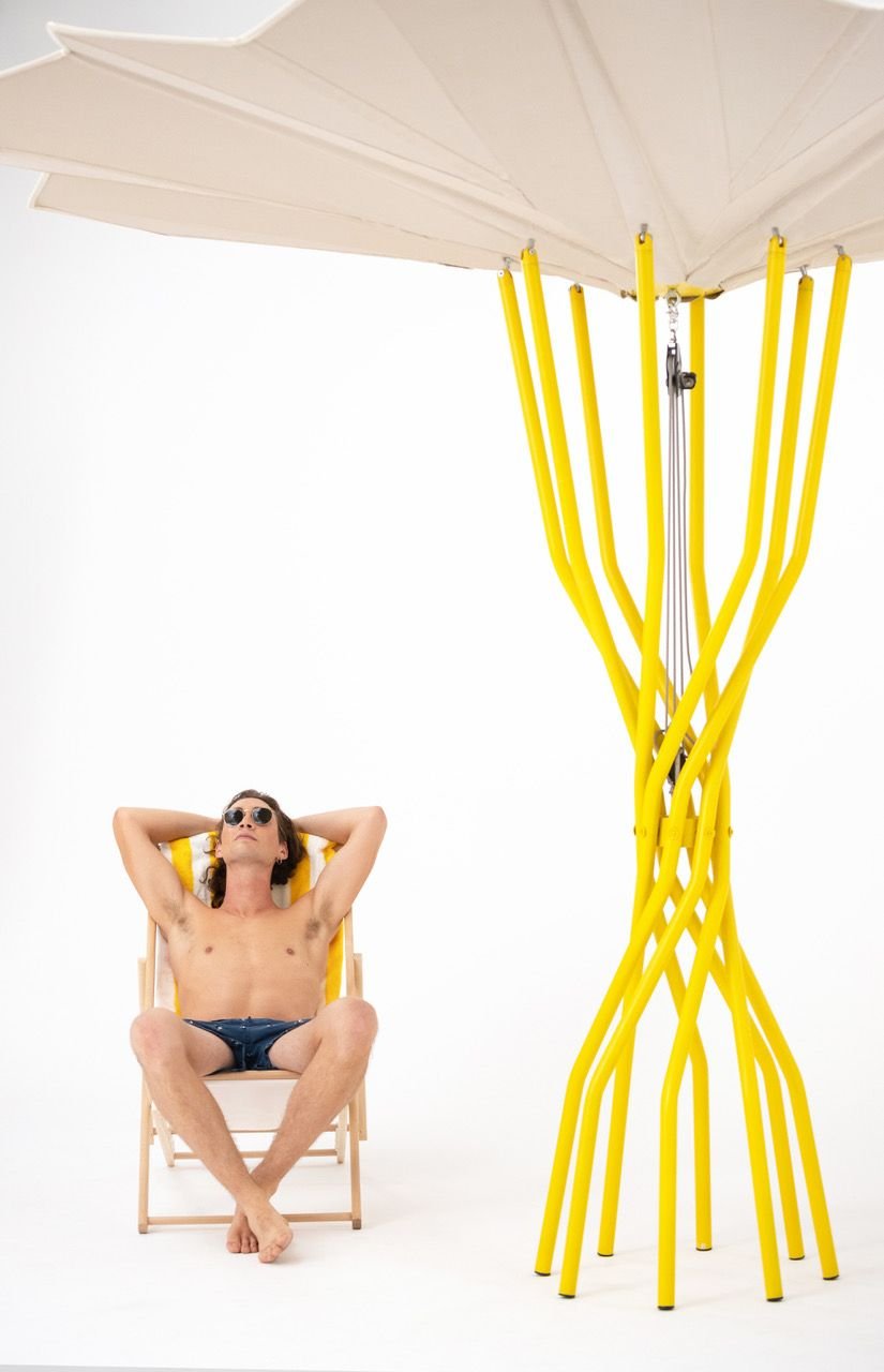 Beach-goer relaxes beneath a Carlo Ratti-designed Sammontana sustainable beach umbrella. 