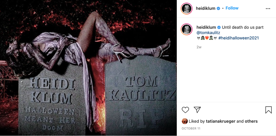 Heidi Klum poses on top of two prop tombstones for her Halloween 2021 festivities.