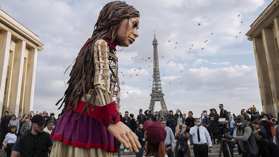 Little Amal greets fans in front of Paris' Eiffel Tower.