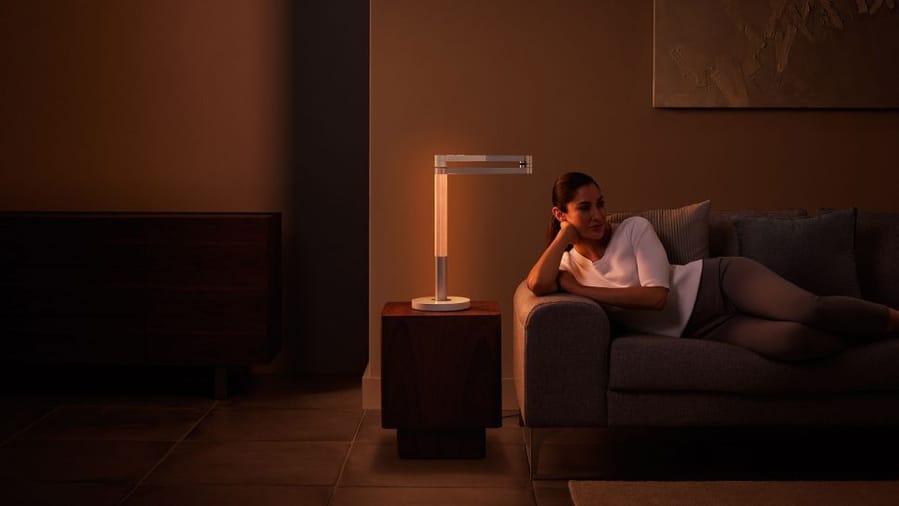 Woman enjoys the warm orange glow coming from her Dyson Lightcycle. 