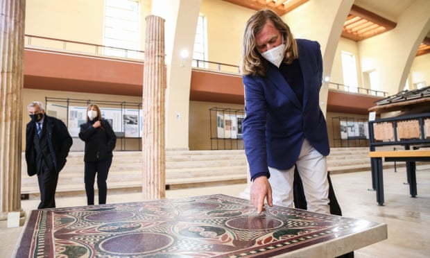Passerby take in the ancient Roman mosaic at its new home in the Museum of Roman Ships.