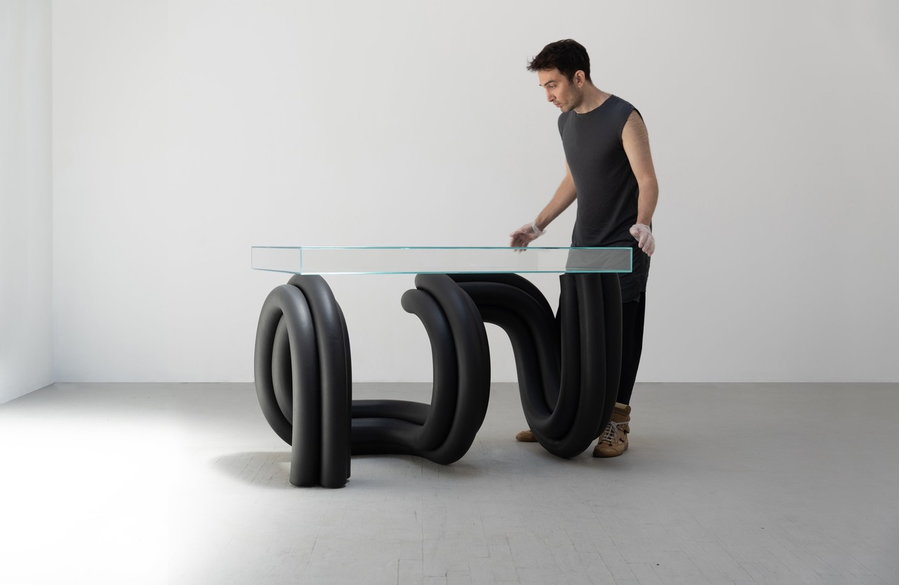 Man adjusts a sculptural glass table by Ara Thorose.