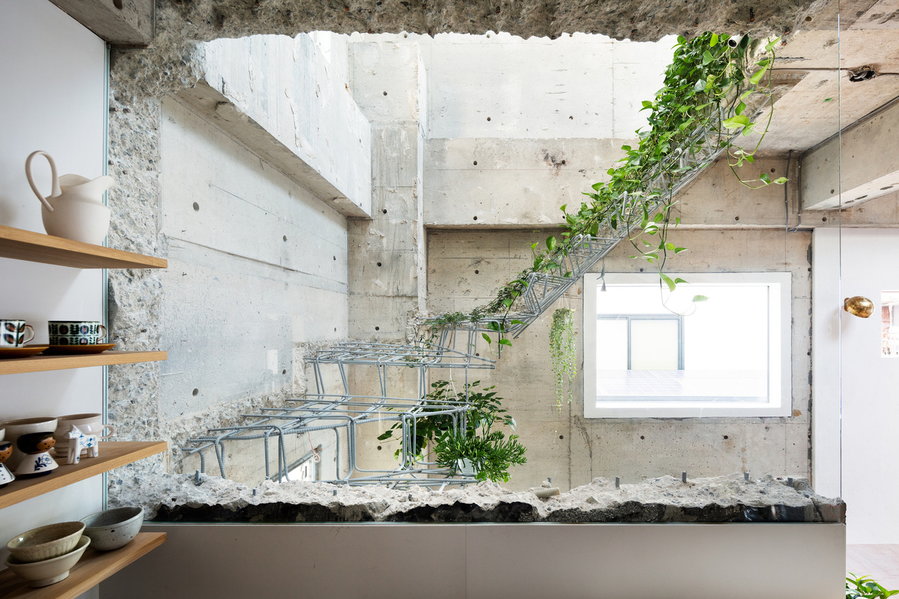 Decorative rebar staircase lined with plant life inside MAMM Design's renovated Tokyo residence. 