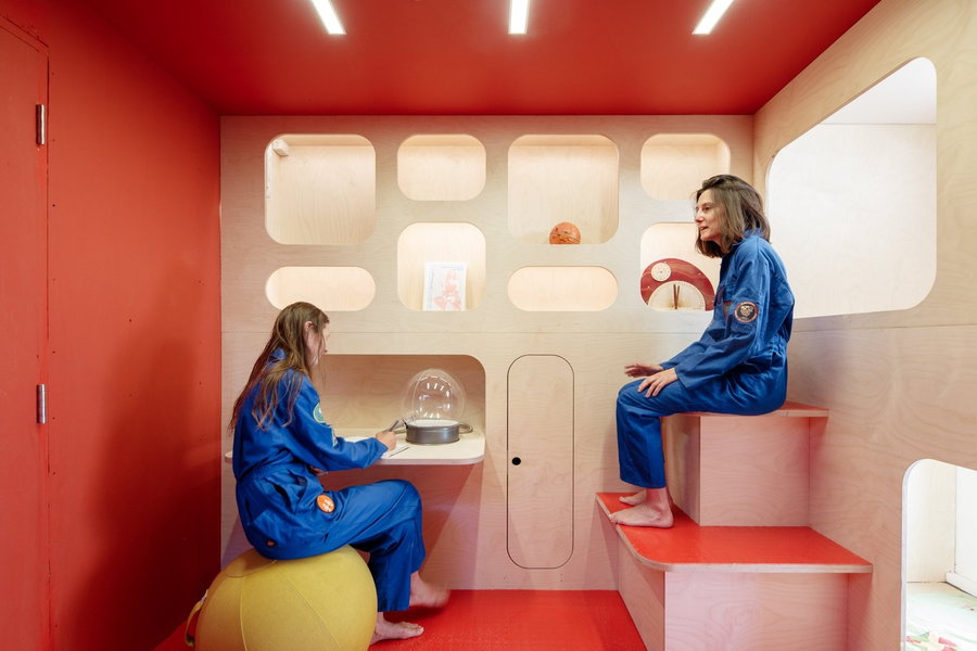 Two women sit inside the Martian House's retro-futuristic interiors.