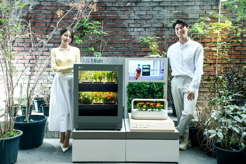 Man and woman proudly display the LG Tiuun smart gardening appliance at CES 2022.