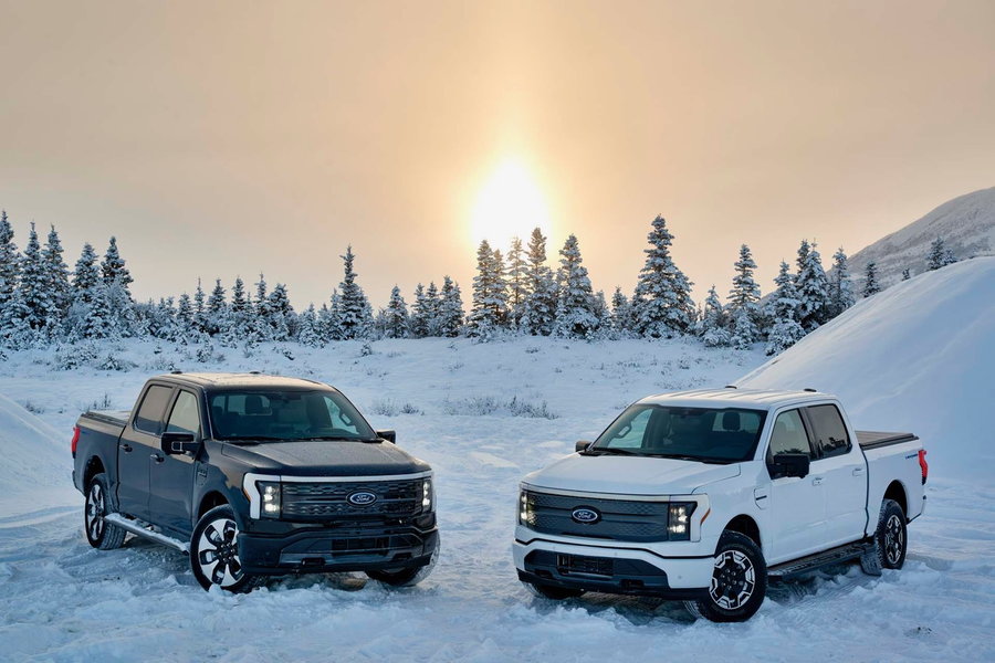 Black and white versions of Ford's new F-150 Lightning EV in the snow. 