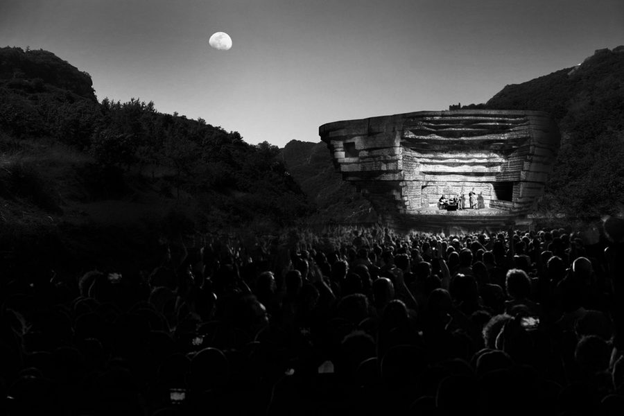 Black and white photo shows an attentive crowd admiring the band playing at the Chapel of Sound, with the moon visible in the sky just beyond.