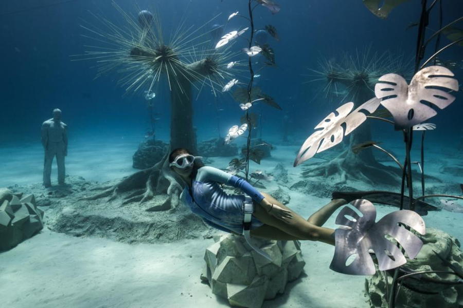 Woman swims through artificial plants and sculptures at the MUSA underwater art museum off the coast of Cancún. 