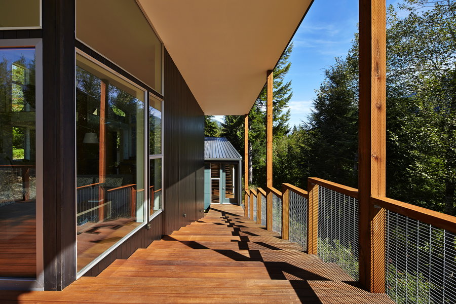 A rustic outer deck encircles the cabin's main volume. 