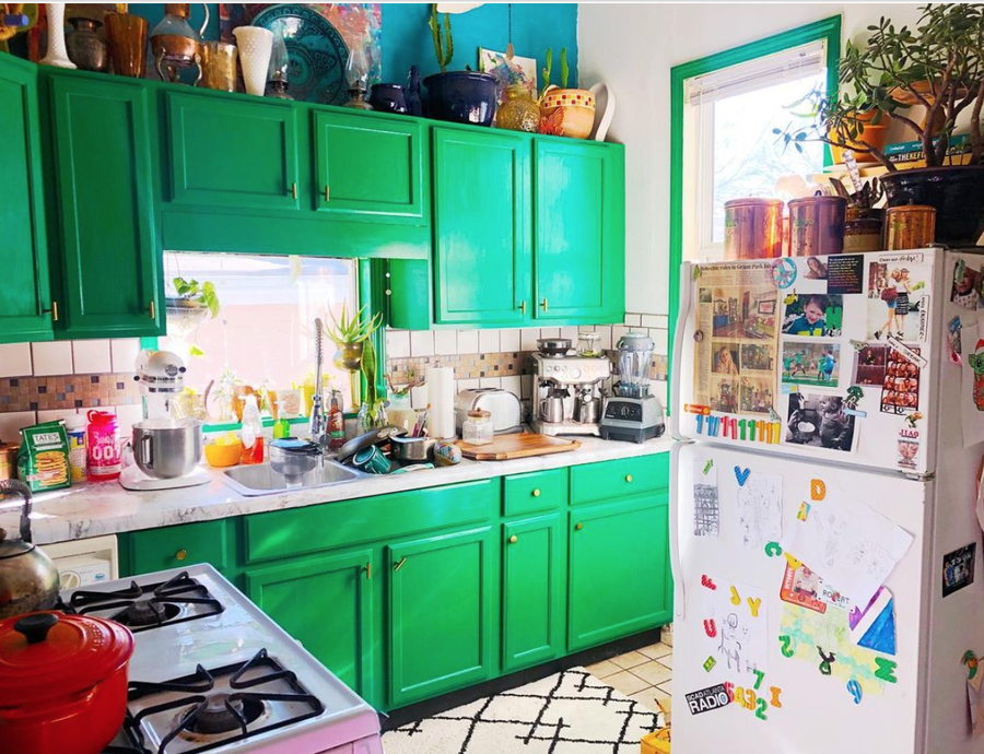 Cluttercore kitchen space with bright green cabinets.