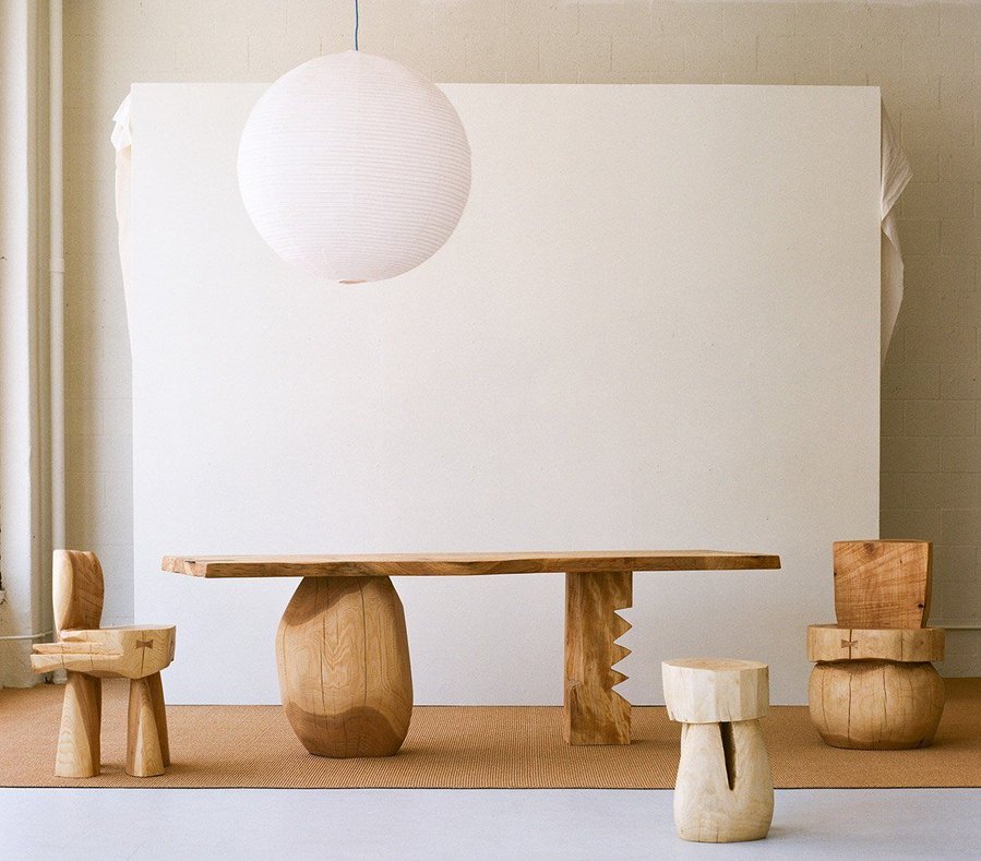 Organic brutalist living space embraces clunky wooden furnishings, geometric fixtures, and a soothing neutral backdrop. 