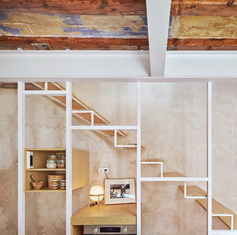 A closer look at the exposed stairway and shelving on the first floor of the Twobo-restored 5x5-meter Barcelona home.