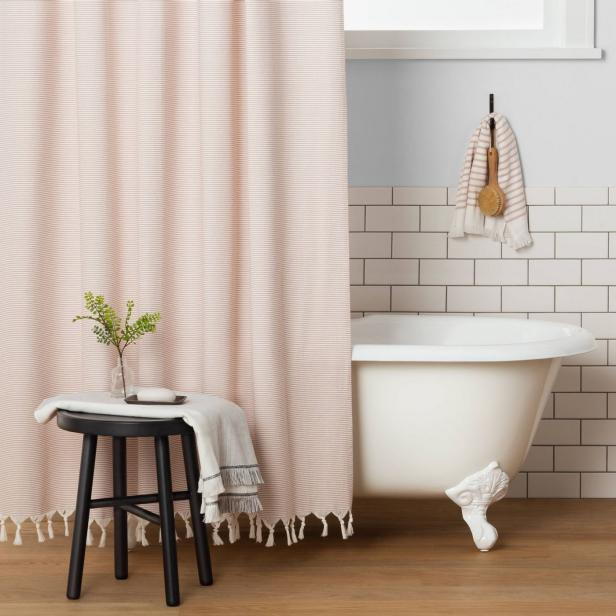 A plain white bathtub adorned with several soft decor accents from Chip and Joanna Gaines' new Target furniture collection.
