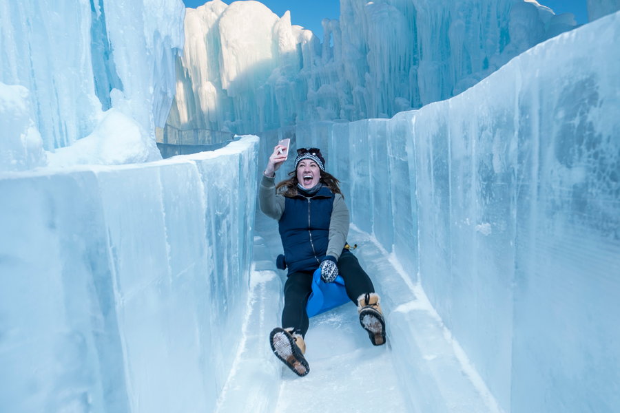 Happy woman slides down an icy slide in one of Brent Christensen's Ice Castles. 