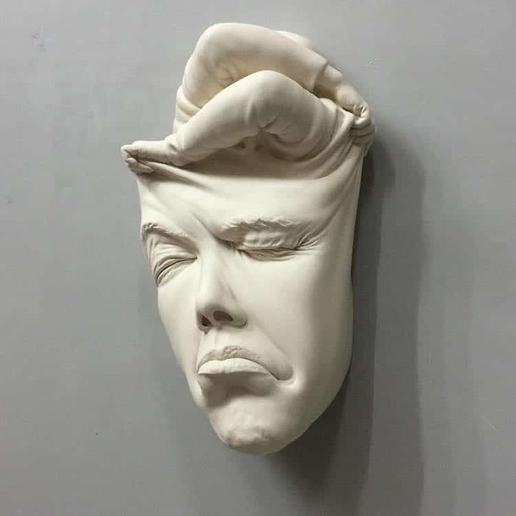 Surreal ceramic by Johnson Tsang shows a face being pushed and pulled apart by body-less hands.
