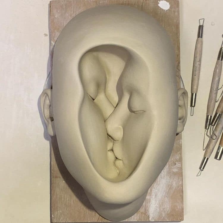 Surreal ceramic by Johnson Tsang shows two faces kissing inside one head.