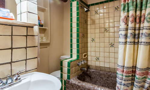 Deep soaking mosaic tiled tubs with bright Mexican tiled shower on top of thick adobe (mud) walls with hand crafted nicho vanity.