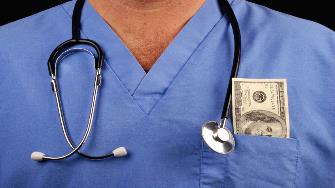 A close-up image of a male medical worker in scrubs with cash in his pocket. 
