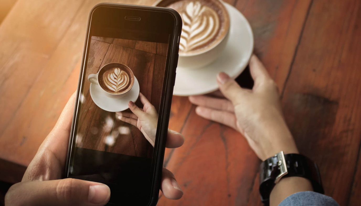 woman taking photo of coffee with smart phone