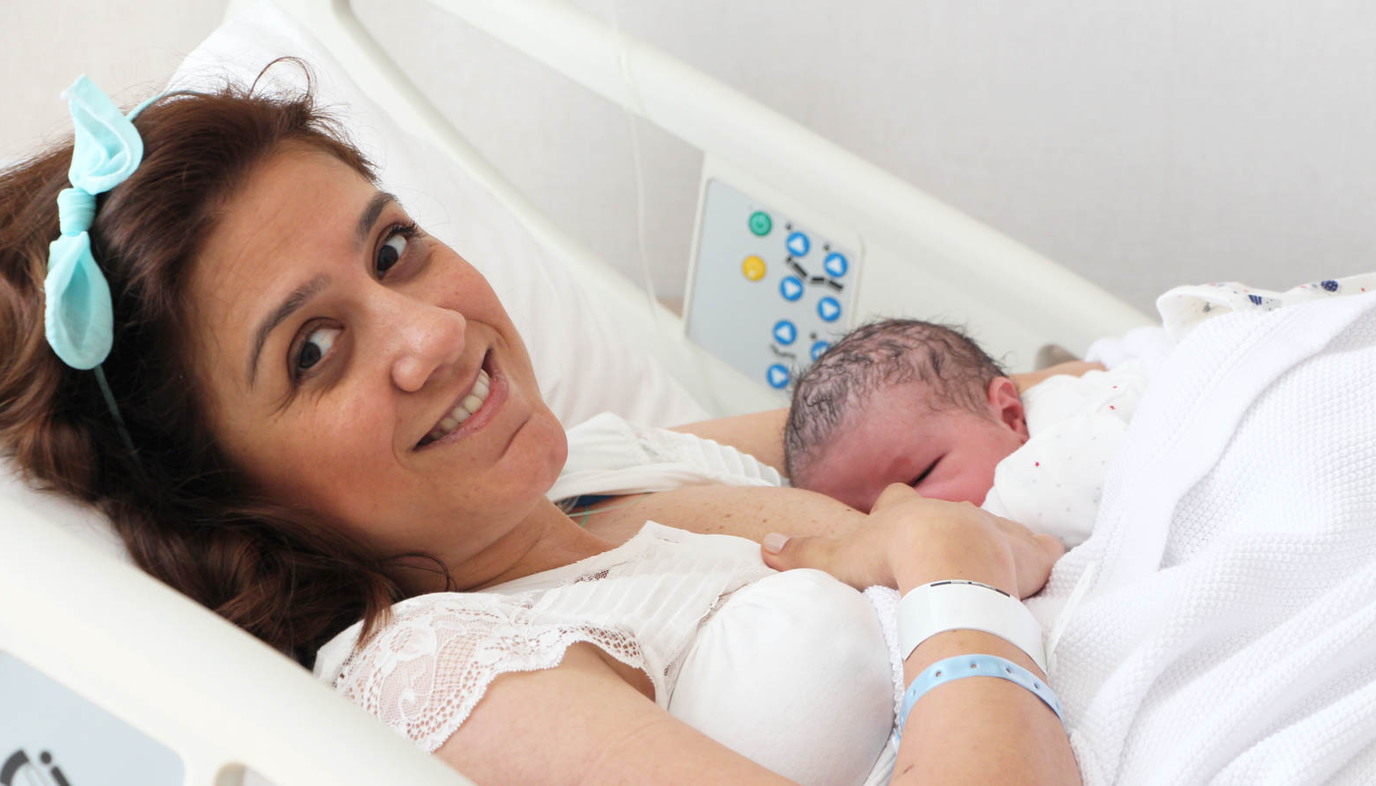 mom in hospital bed breastfeeding newborn