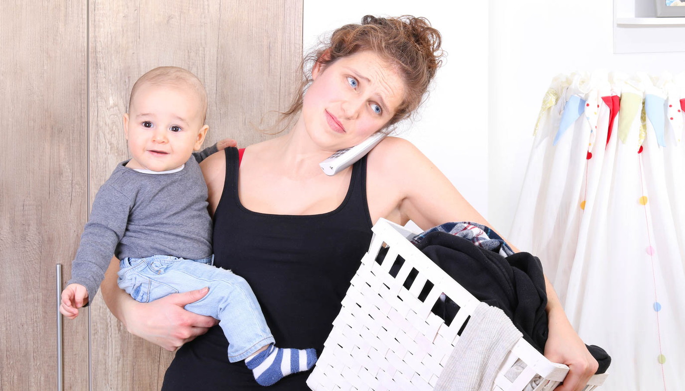 mom on the phone holding laundry basket and child