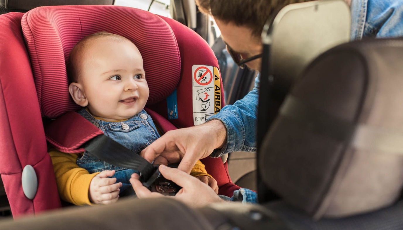 Father fastening baby into baby seat