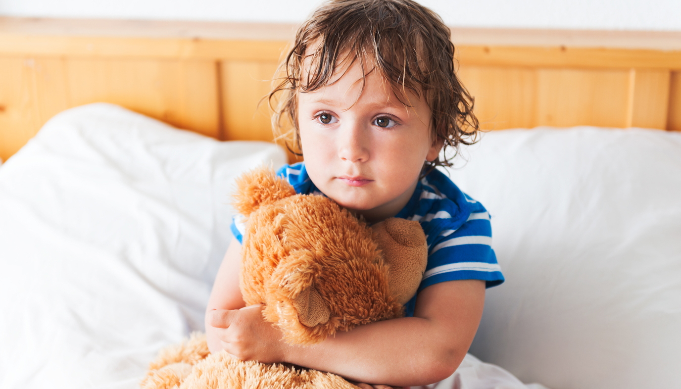 child holding teddy bear in bed