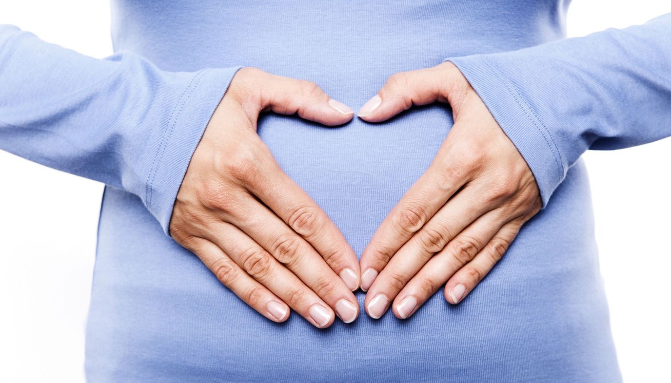 pregnant woman holding hands in heart shape