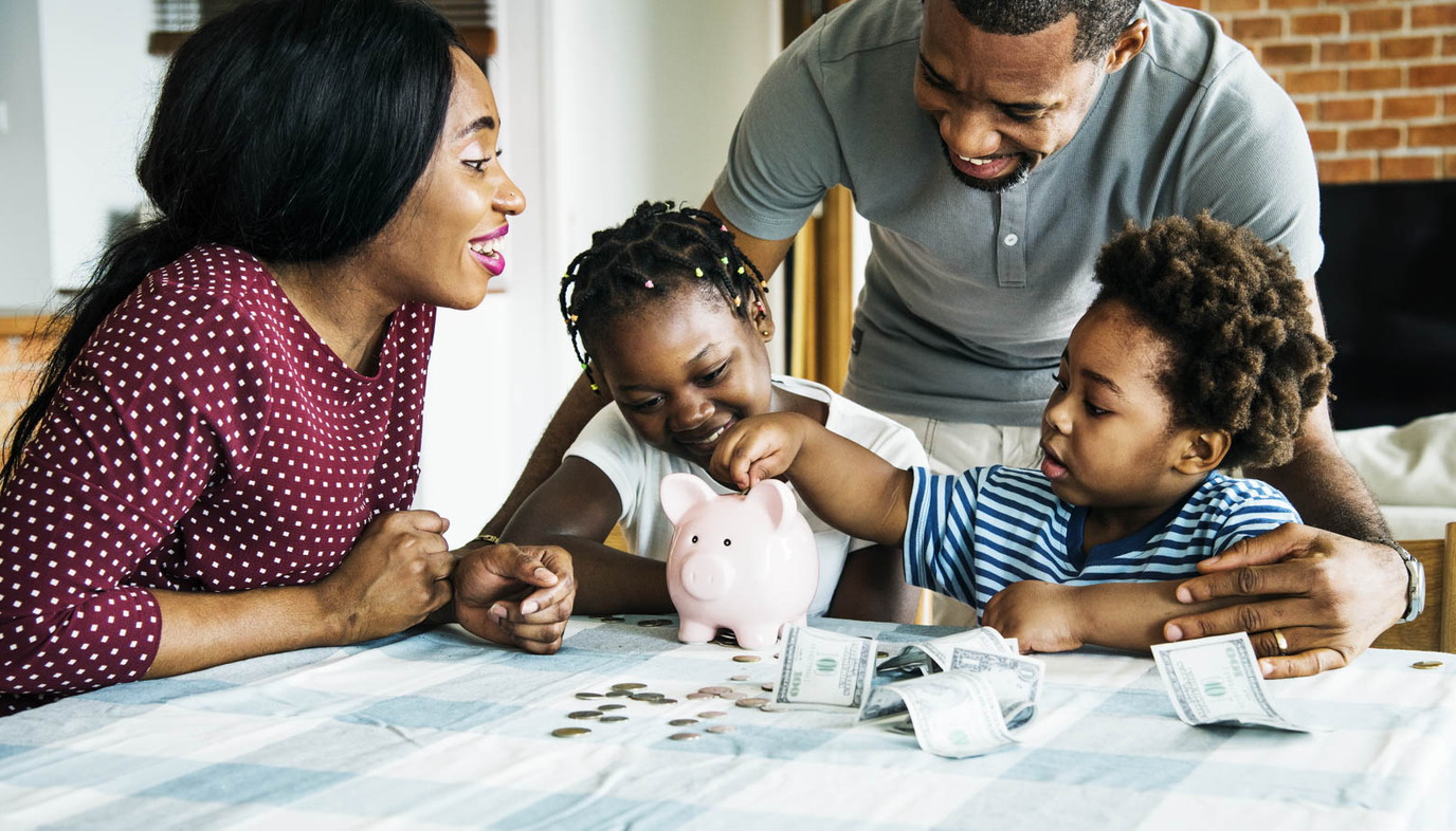 family putting money into a piggy bank