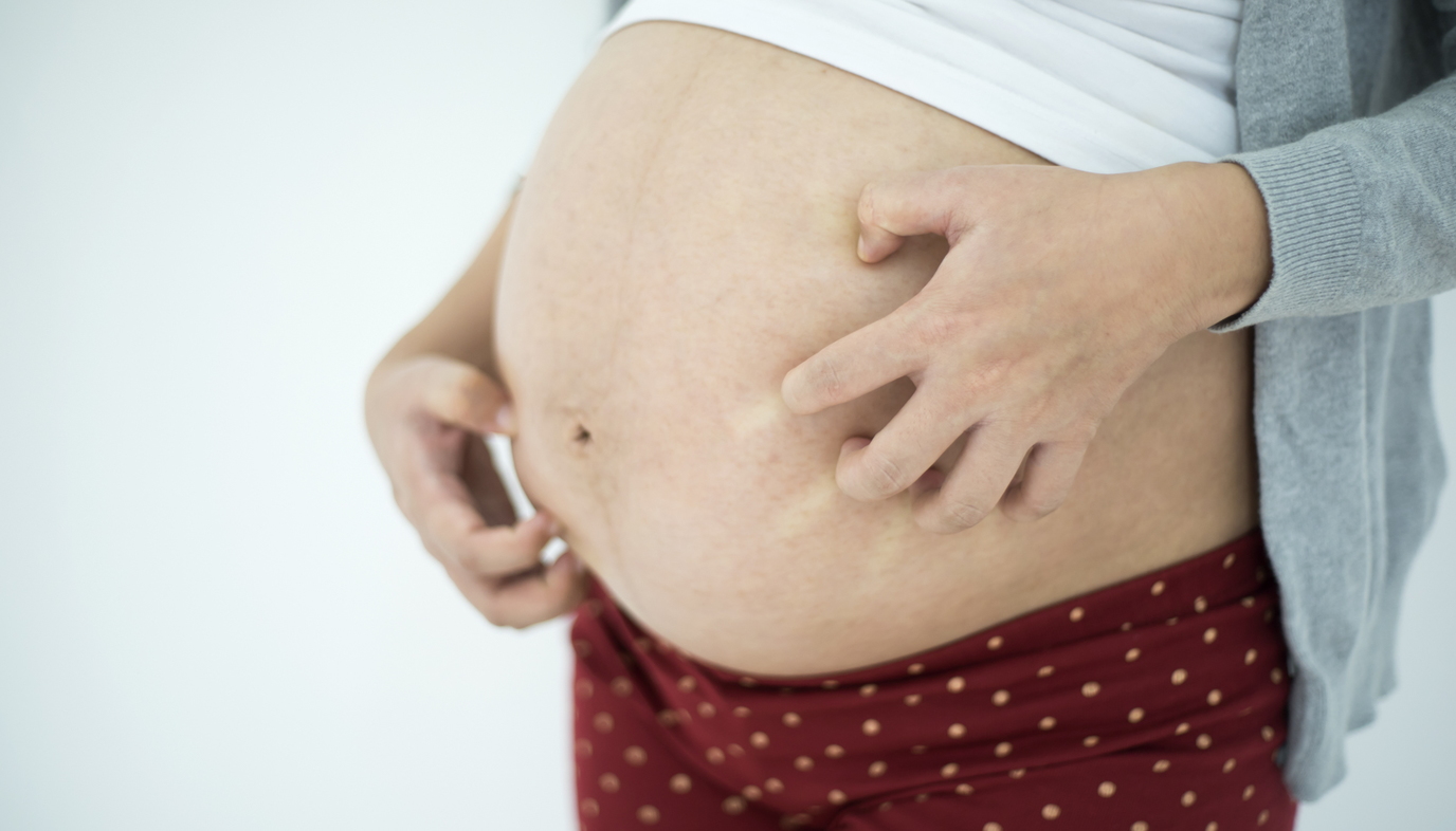 pregnant woman scratching belly