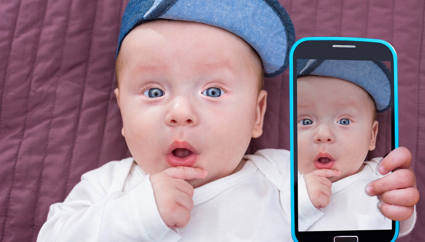 baby holding phone with picture of himself
