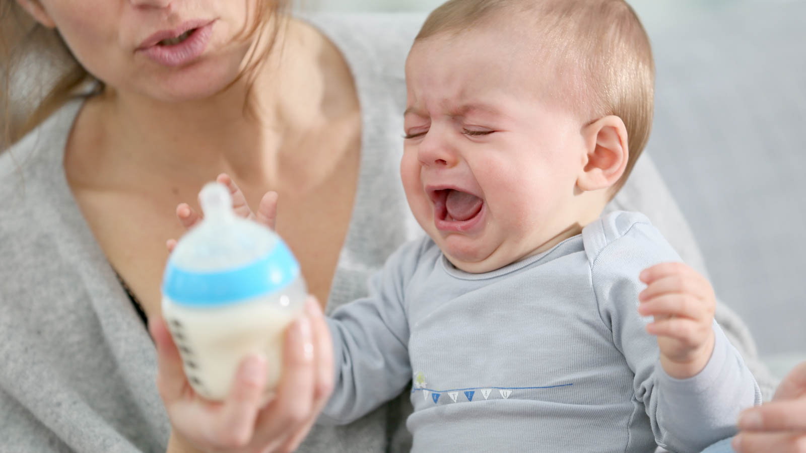 baby crying while mom holds bottle