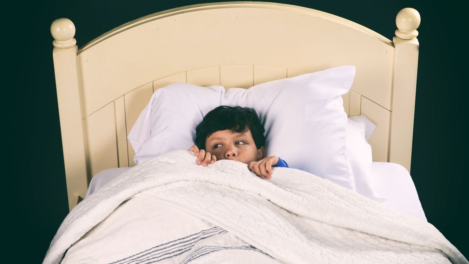 boy in bed under blanket