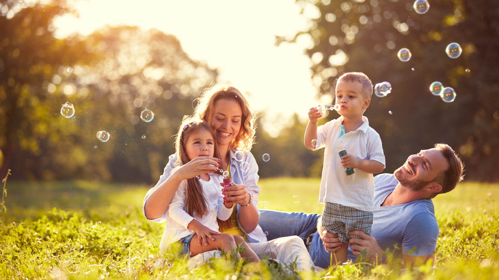 parents blowing bubbles with their kids on a sunny day
