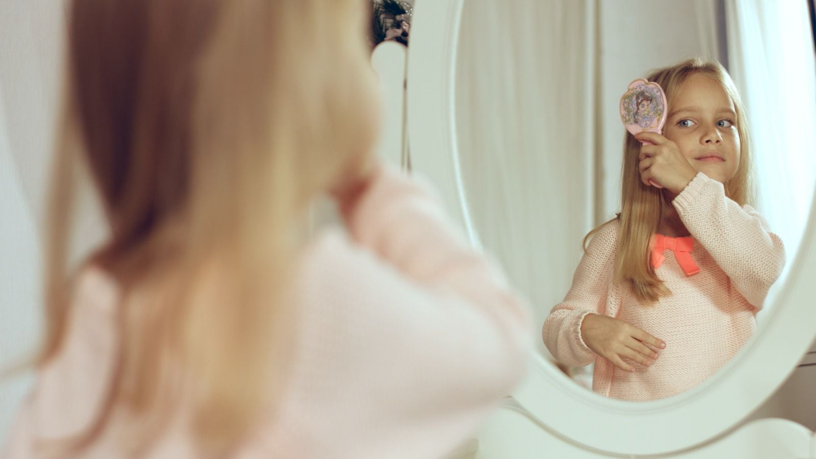 girl brushing hair in front of mirror