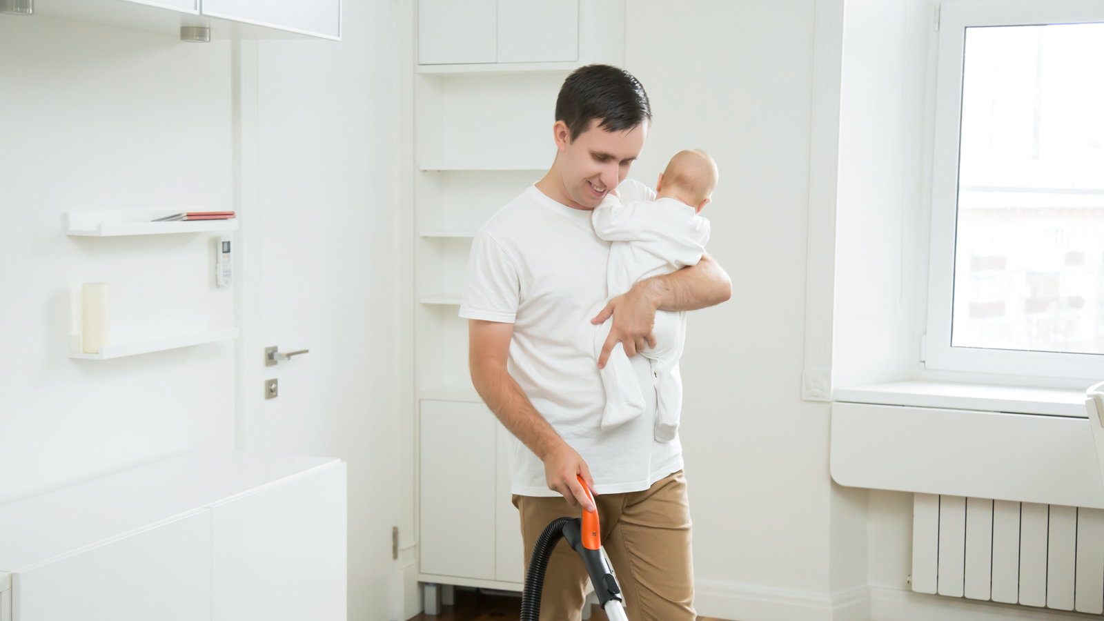 man cleaning house while holding baby