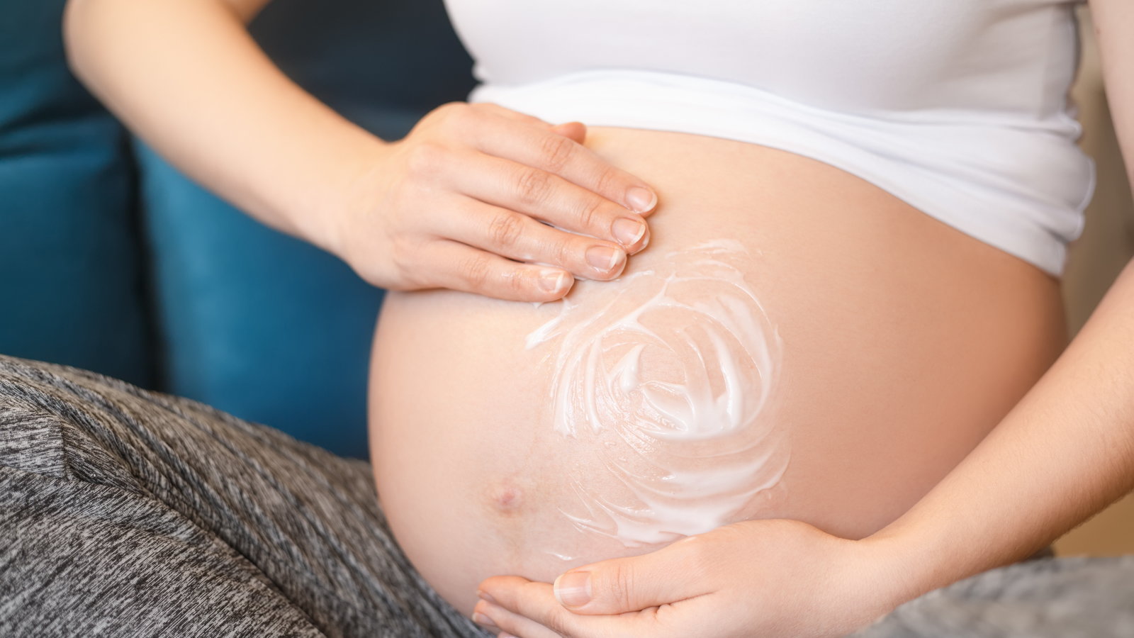 pregnant mom applying lotion to belly
