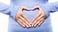 pregnant woman holding hands in heart shape