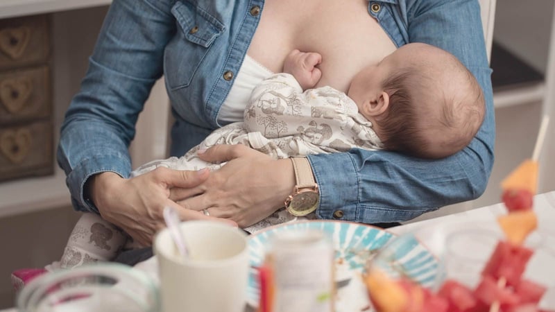 Mother breastfeeding baby at table