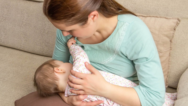 Mother breastfeeding baby on couch