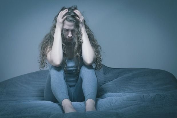 frustrated woman looking down and holding onto her head