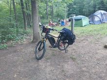 The heavily-laden e-bike is now at a state park campsite. Other campers with their tents are in the background.