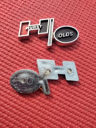 Hurst Olds Emblem. Aftermarket. I believe that these are 73-75 console emblems. Other suppliers indicate them as being used on 69-72 also. Emblem measures 2 1/2" x 1 1/4". They are made of molded plastic chrome. Does not have sticky back.
$20 each.