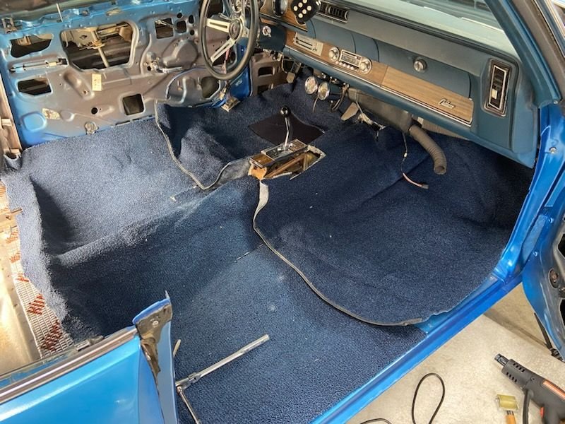 Well, I laid the carpet out in the back and the front just to try to center it! The holes for the console didn't quite fall where I thought they would, but I tucked it un up under the dash and moved it all around, so it looked right. I used a few 60 bags of sand to pull it down on the hump and started cutting seat belt and seat mount holes. I started with the seatbelt next to the console first. 